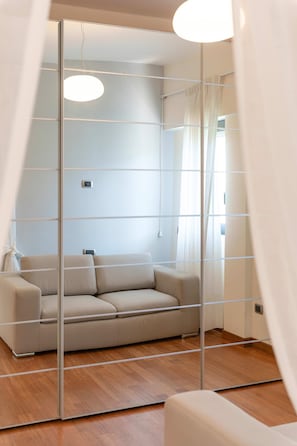 Ein modernes Wohnzimmer mit einer Couch, einem Spiegel und einer Lampe.