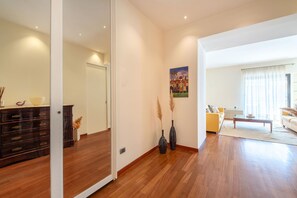 Een ruime woonkamer met een houten vloer, een bank, een salontafel en een schilderij aan de muur.