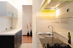 Cozinha moderna com pia de aço inoxidável, fogão a gás e armário com porta de vidro.