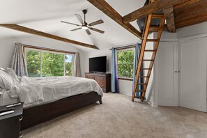 Une chambre à coucher avec un lit, un téléviseur, un ventilateur de plafond, une fenêtre et une échelle en bois.