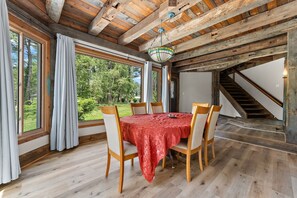 A dining area with a table set for four, wooden chairs, and a view of the outdoors through large windows. - Spacious 5BR Retreat in Peaceful Michigan City (Michigan City)