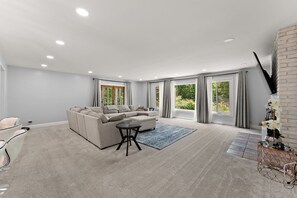 Un salon moderne avec un canapé d’angle, une petite table ronde et un tapis bleu.