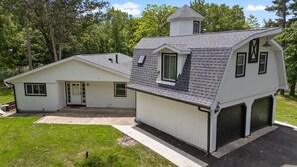 Une maison à deux étages avec un garage, un petit abri attenant et un toit en pente.