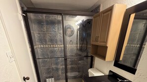 Un baño con ducha, inodoro, lavabo y espejo.