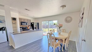 Cocina moderna con una isla central, mesa de comedor con sillas y vista al patio trasero.