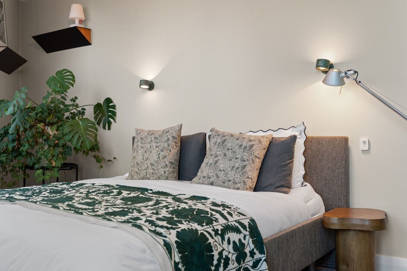 Ein Schlafzimmer mit einem Bett, einer Nachttischlampe und einer Topfpflanze.