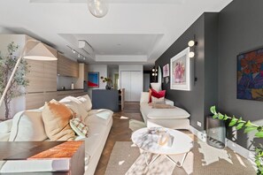 A modern living room with a sofa, coffee table, and artwork on the walls. - The Margot by Homello | Designer Apartment | Sky Tower Views | Ponsonby (Freemans Bay)