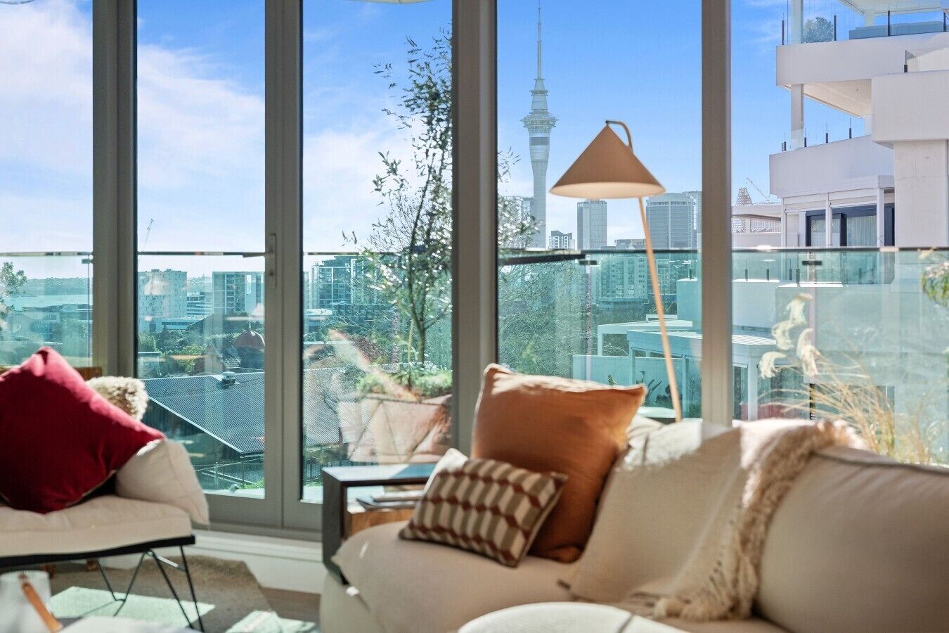 A modern living room with a large window overlooking a cityscape, including a prominent tower.