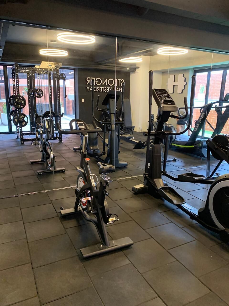 A gym with various exercise equipment, including treadmills and weight machines, arranged on a tiled floor.