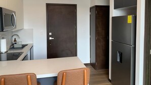 Una cocina moderna con encimera blanca, electrodomésticos de acero inoxidable y una puerta de madera oscura.