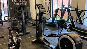 Un gimnasio con diversos equipos de ejercicio, incluyendo cintas de correr, bicicletas estáticas y máquinas de pesas.