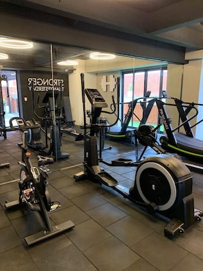 Un gimnasio con diversos equipos de ejercicio, incluyendo cintas de correr, bicicletas estáticas y máquinas de pesas.
