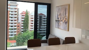 Una cocina moderna con una isla grande, una zona de comedor con sillas y vistas a la ciudad por la ventana.