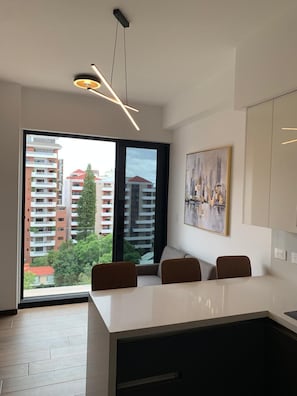 Una cocina moderna con una isla grande, una zona de comedor con sillas y vistas a la ciudad por la ventana.