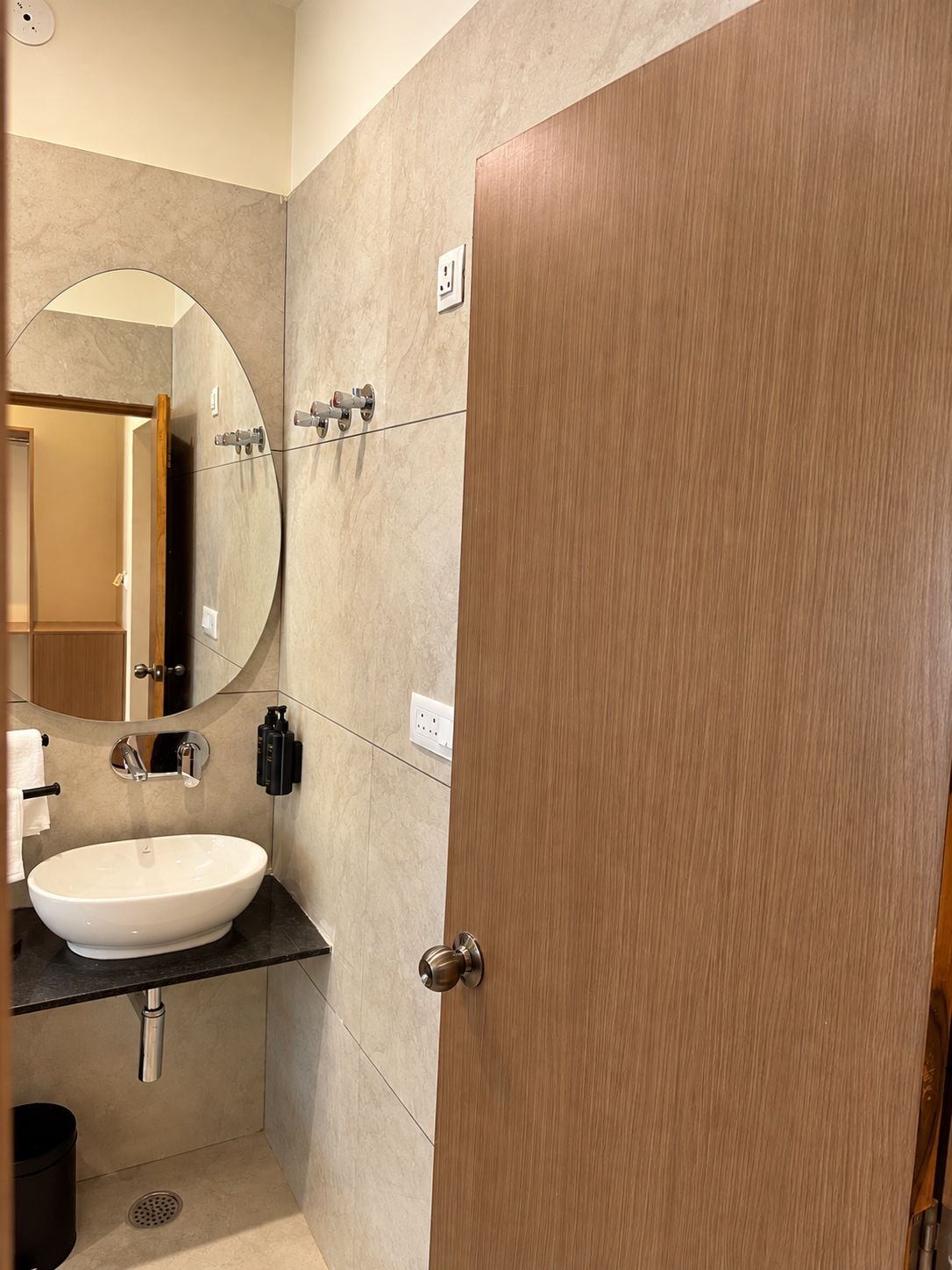A modern bathroom with a round mirror, a sink, and a door.