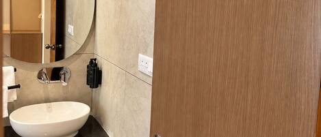 A modern bathroom with a round mirror, a sink, and a door.