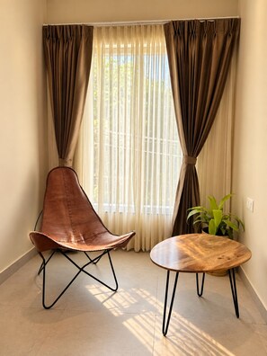 A room with a single leather chair, a wooden table, and a potted plant. - ONE37 HOUSE (Udaipur)