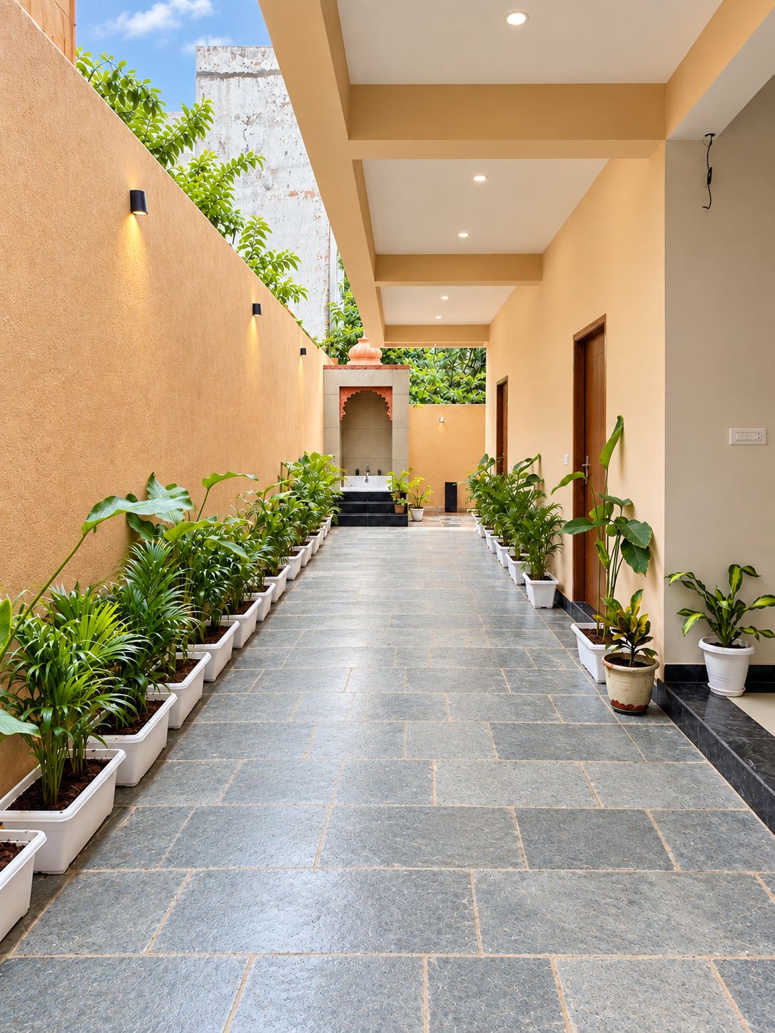 A corridor with potted plants on either side, leading to a door at the end.