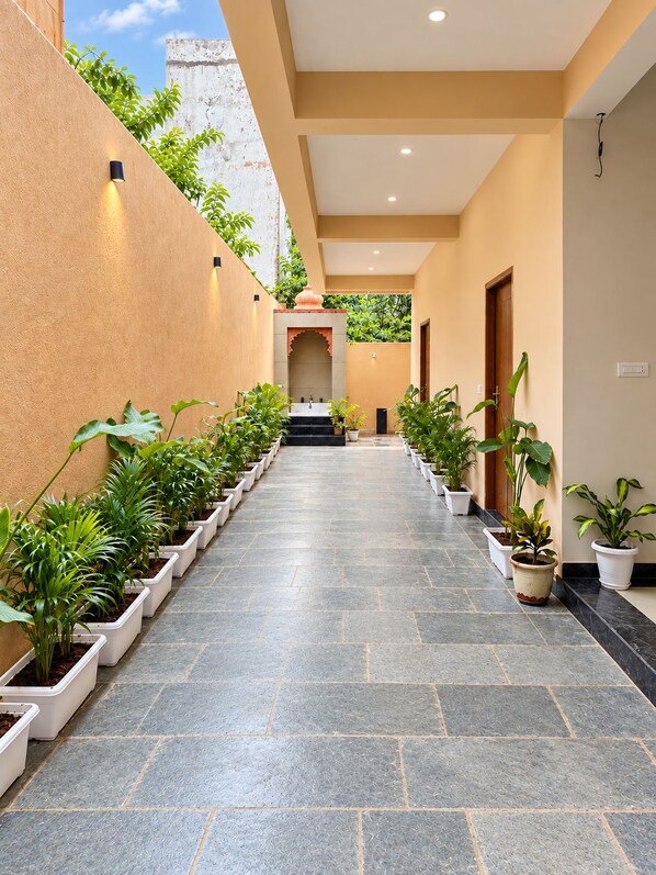 A corridor with potted plants on either side, leading to a door at the end. - ONE37 HOUSE (Udaipur)