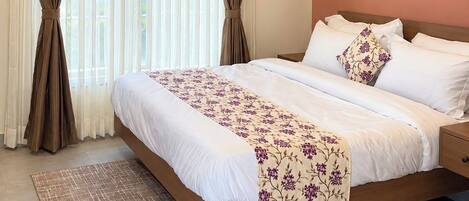 Una camera d'albergo con un letto, tende, un condizionatore d'aria e una ventola a soffitto.