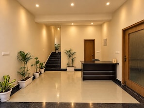 A reception area with a reception desk, a staircase, and potted plants. - ONE37 HOUSE (Udaipur)