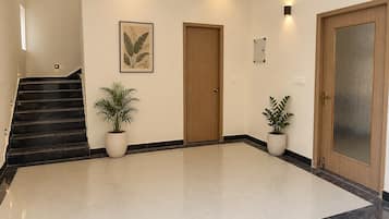 A hotel lobby with a staircase, two doors, and potted plants.