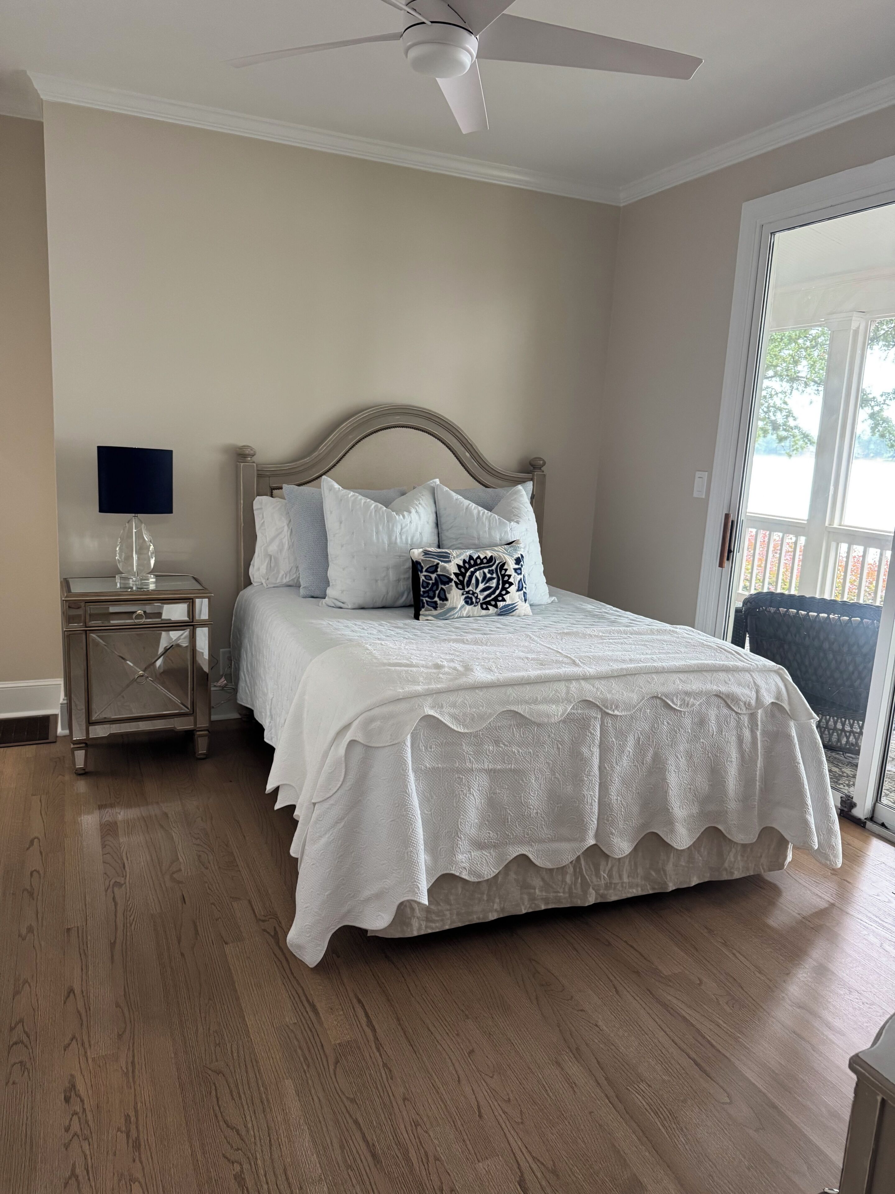 A bedroom with a bed, a nightstand, a lamp, and a ceiling fan.