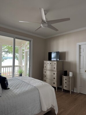 A bedroom with a bed, a dresser, a television, and a ceiling fan. - Charming Lake Oconee Cottage- 3 Bedroom Retreat in Reynolds (Eatonton)