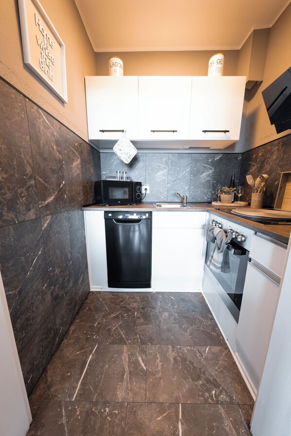 A compact kitchen with a dishwasher, microwave, and oven.