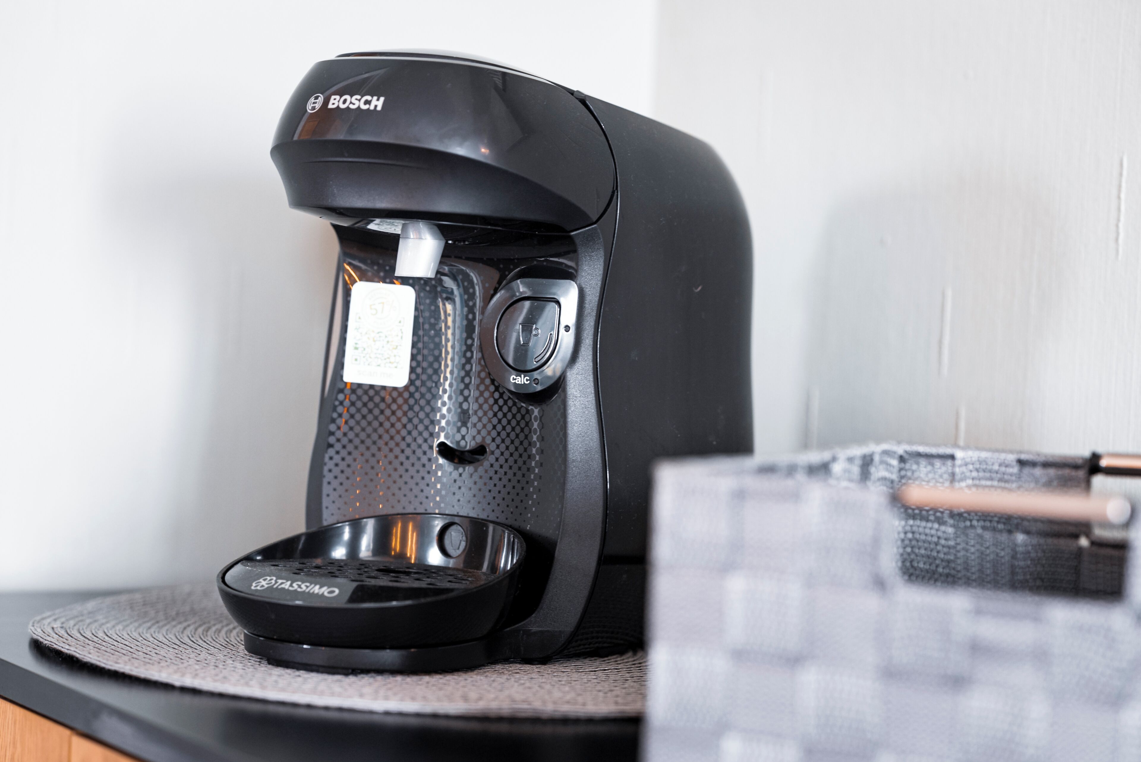 Eine schwarze Kaffeemaschine mit digitaler Anzeige und einer Kapselhalterung auf einer Küchenarbeitsplatte.