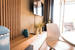 A modern room with a wooden slatted wall, a flat-screen TV mounted above a white console table, and a white chair.