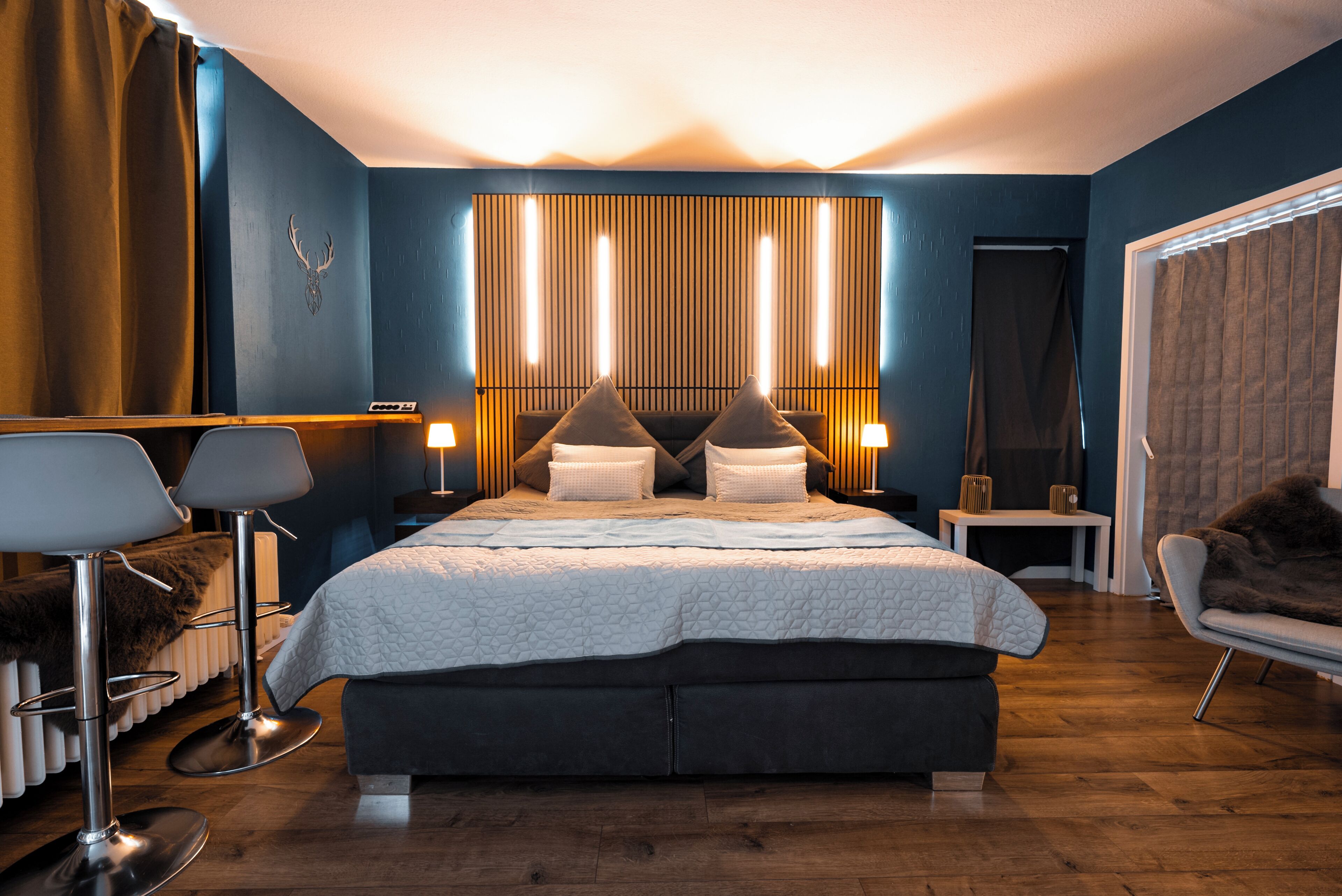 Ein modernes Schlafzimmer mit einem großen Bett, Nachttischen, einem Sessel und einem Spiegel.