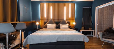 Ein modernes Schlafzimmer mit einem großen Bett, Nachttischen, einem Sessel und einem Spiegel.