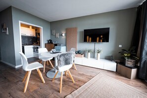 A modern living room with a dining area, a flat-screen TV, and a kitchen in the background. - Vrbo Property (Linz am Rhein)