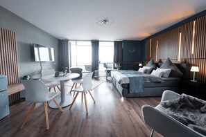 Habitació d'hotel moderna amb llit, zona de seients i televisió.