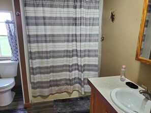 A bathroom with a striped shower curtain, a white sink, and a mirror.