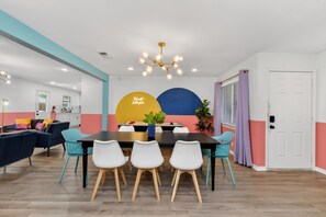 A modern dining area with a black table, white chairs, and a unique ceiling light fixture. - Modern NRH Retreat | Pool, BBQ & Sleeps 10 (Fort Worth)