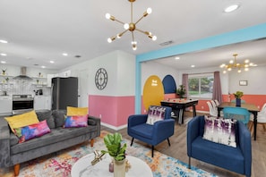 A modern living room with a grey sofa, blue armchairs, a coffee table, and a colorful rug.