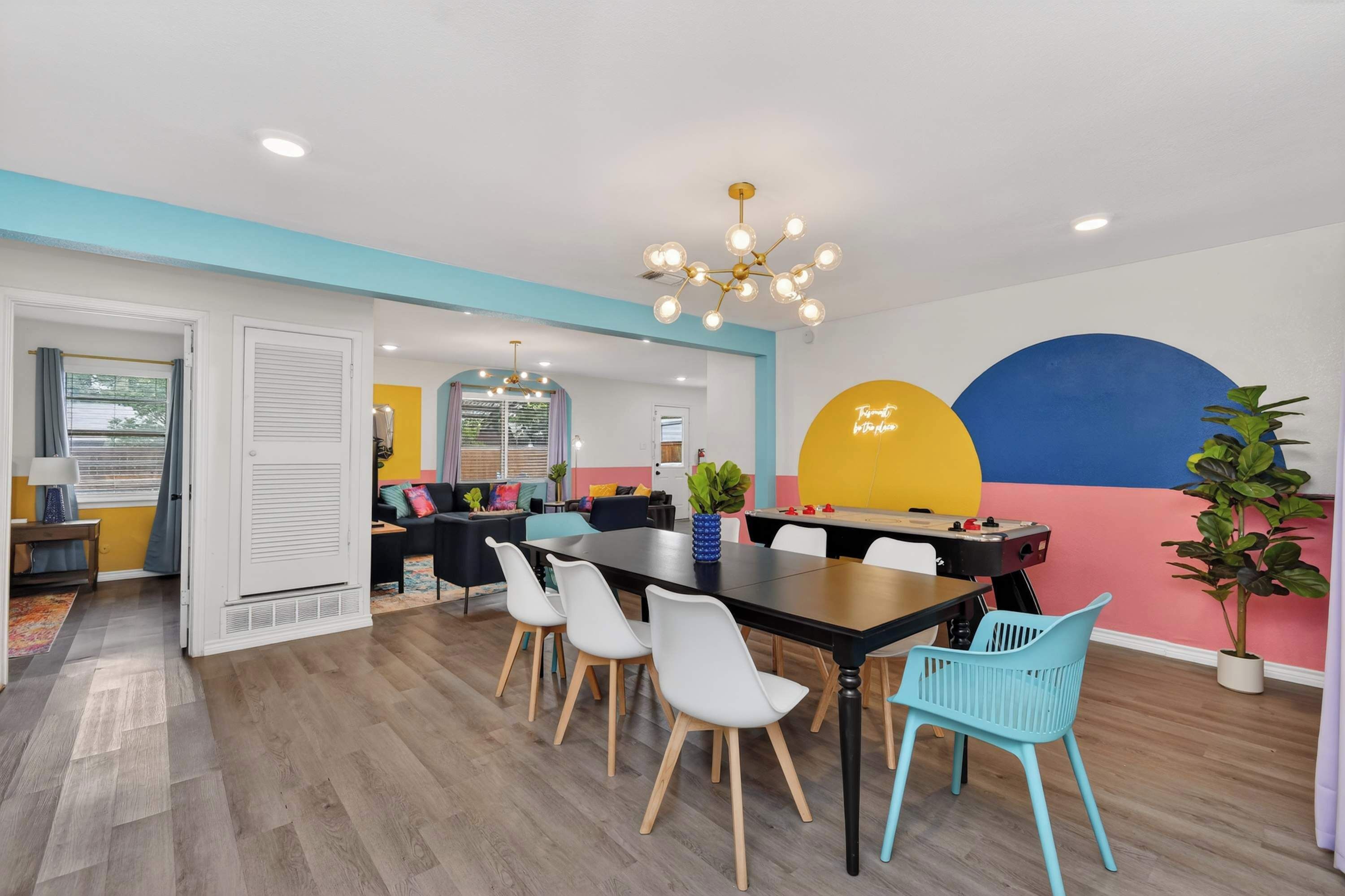 A modern dining area with a black table, white chairs, and a colorful wall mural.