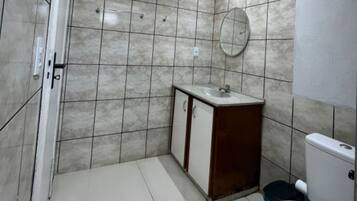 A bathroom with a tiled floor, a sink with a mirror, and a toilet.