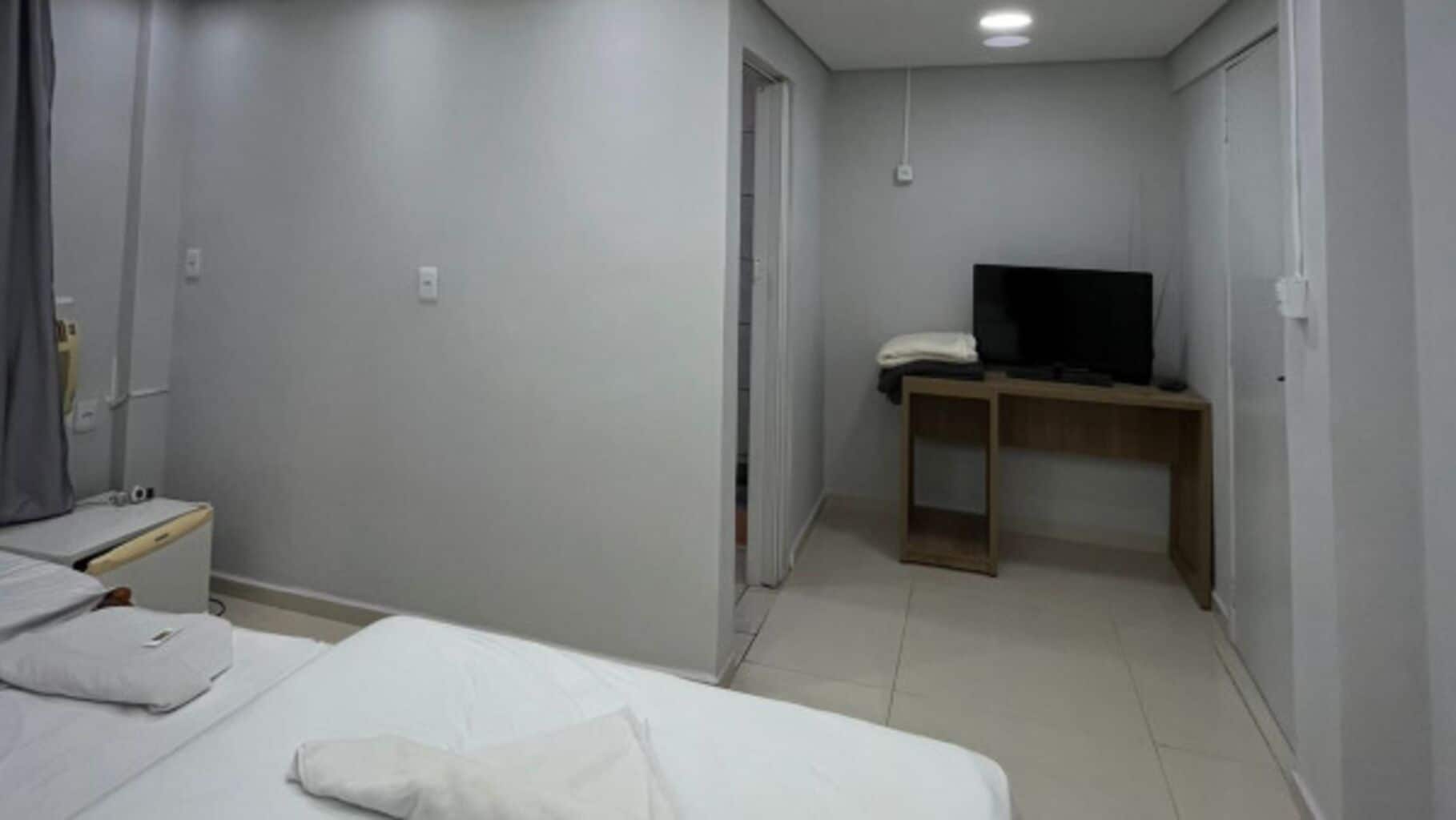Habitación de hotel con cama, escritorio y televisión.