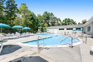 Ein Poolbereich mit Liegestühlen, Sonnenschirmen und einem Gebäude im Hintergrund.