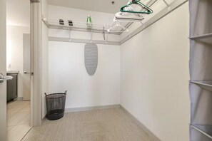 Een hoek van een kamer met een wasmand, een kledingrek en een wanddecoratie met patroon.