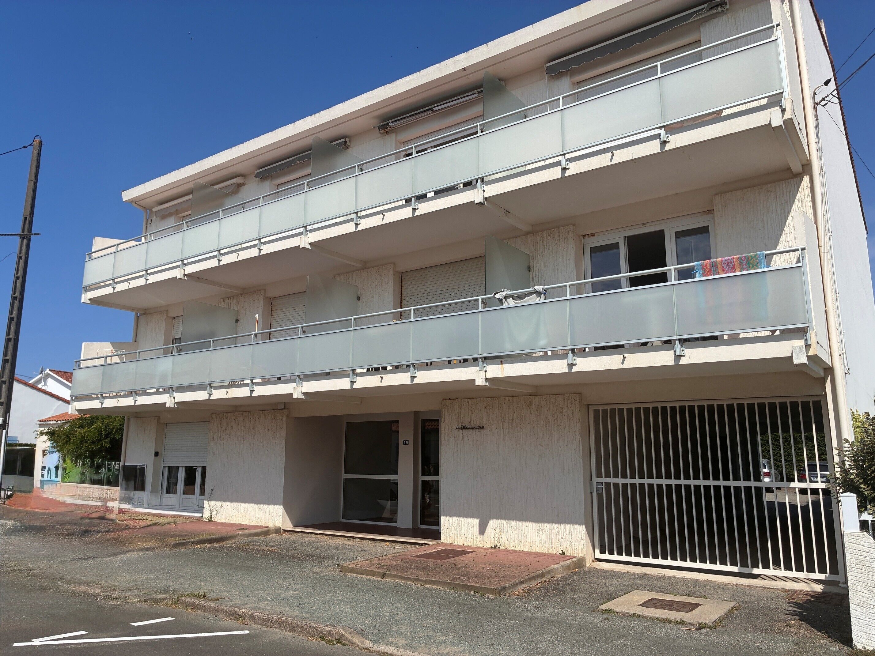 Un edifici de diversos pisos amb façana plana, entrada tancada per una reixa i un balcó amb barana metàl·lica.