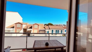 Ein Balkon mit Tisch und einer Vase, mit Blick auf eine Reihe von Gebäuden mit roten Ziegeldächern.