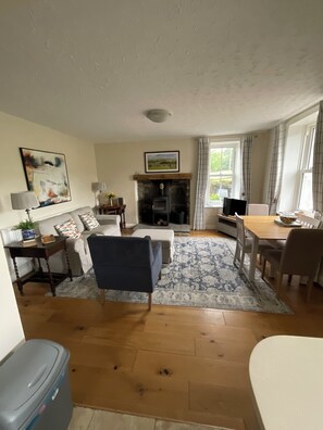 A living room with a fireplace, sofa, armchair, dining table, and a television. - Stunning property. Adults only. Pet friendly. Close to all youre going to need. (Leyburn)