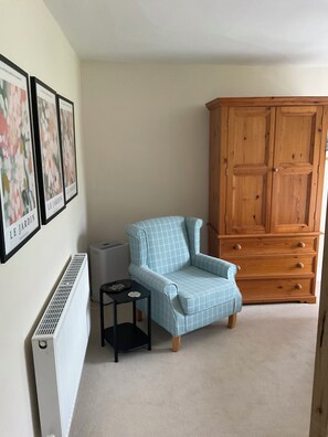 A room with a blue armchair, a wooden cabinet, a radiator, and framed pictures on the wall. - Stunning property. Adults only. Pet friendly. Close to all youre going to need. (Leyburn)
