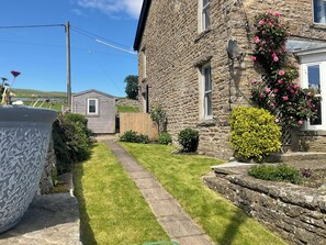 A stone building with a paved pathway leading to a wooden door, surrounded by well-maintained grass and shrubs. - Stunning property. Adults only. Pet friendly. Close to all youre going to need. (Leyburn)