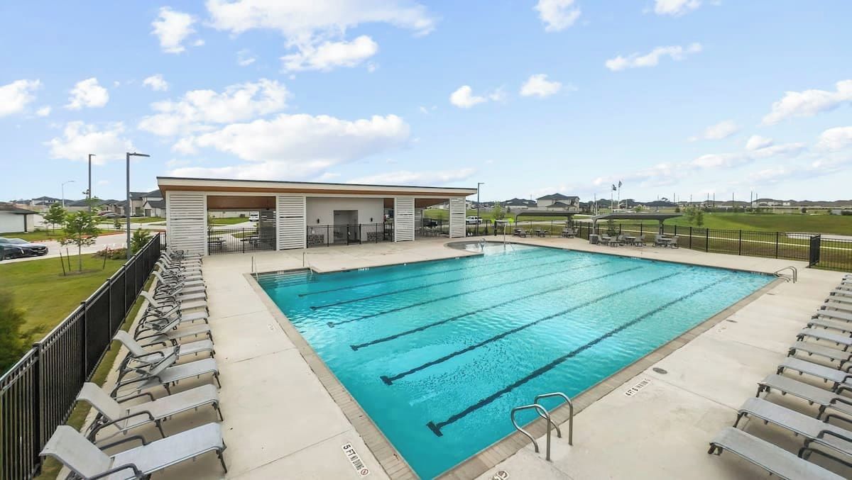 A swimming pool with multiple lanes, a covered seating area, and a view of the surrounding landscape.