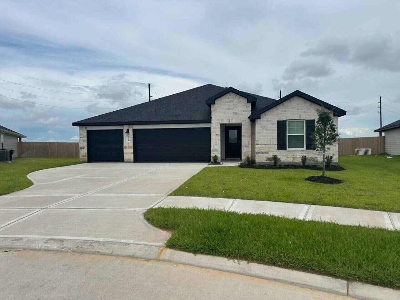 A two-story house with a garage, a lawn, and a small tree.